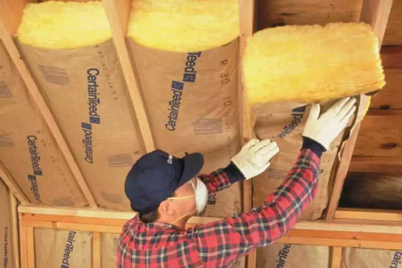 Fiberglass insulation installer, insulating home's ceiling.